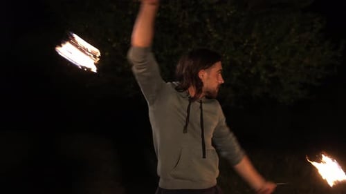 Man Fire Spinning with Flame Batons at Night