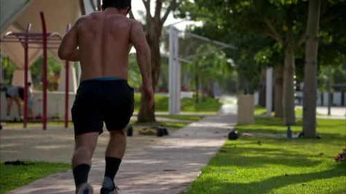 Athletic Man Runs Through Park on Sunny Day