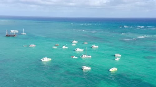 Aerial pan showing leisure boats anchored in shallows of Caribbean
