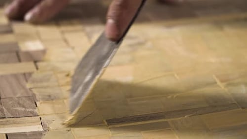 Close shot of a spatula spreading wooden paste on a wood