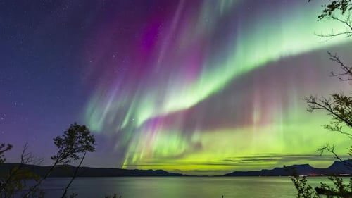 Northern lights timelapse over calm lake in Abisko, Sweden