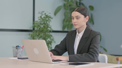 Smiling Woman Typing on Laptop in Office Setting