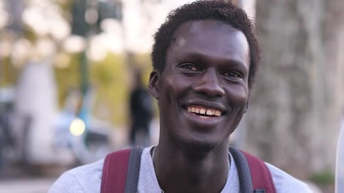 relaxed young black man on the street laughs at the camera