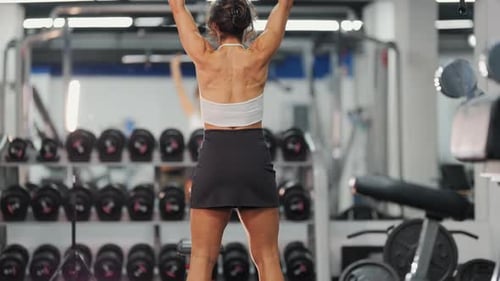 Muscular Woman Performing Overhead Barbell Press in Gym