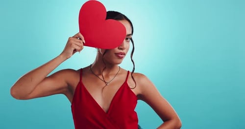 Woman, paper heart and valentines day in studio with choice, date or sign with smile by blue