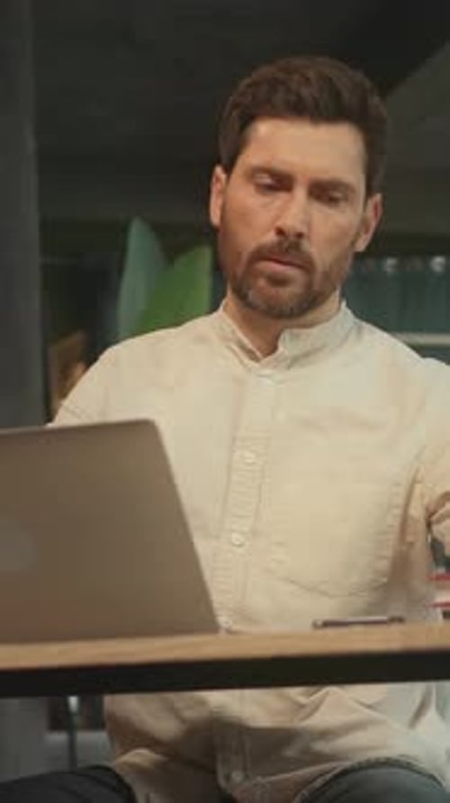 Portrait of Man Sitting at Desk Use Laptop and Made Notes in Notebook in the Office Camera Moving