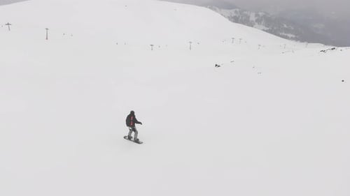 Snowboarder Descending a Snowy Mountain Slope