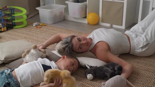 Woman and Child Resting Indoors with Plush Toys