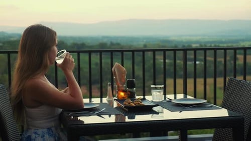 Young Woman Enjoying Peaceful Outdoor Dining Experience on Balcony
