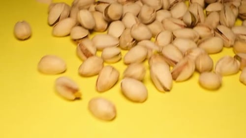 Pistachios Falling onto a Yellow Surface