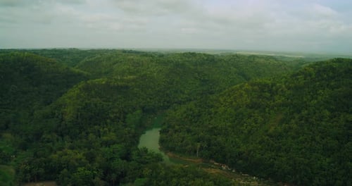 Aerial river flowing through tropical forest at sunrise with morning mist