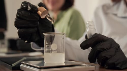 Femme faisant couler de l'huile essentielle dans un bécher pendant une master class de parfum