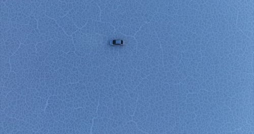 Isolated car turning in circles on white surface of Bonneville Salt Flats, Utah. Aerial Top-down asc