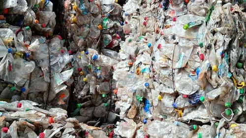 Varias pilas de basura plástica transparente comprimida en una fábrica de reciclaje de residuos al aire libre. Sl