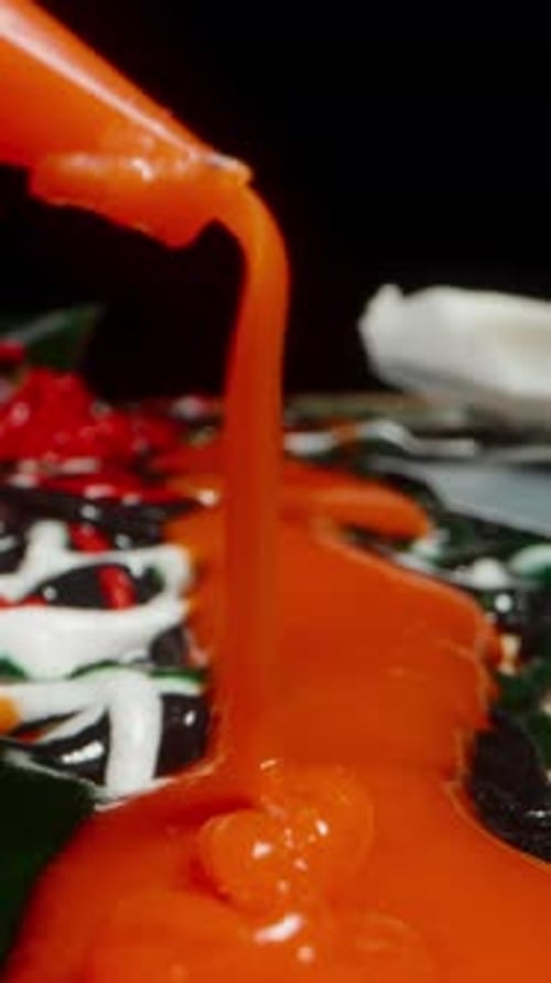 Vertical video. The last drops of red sugar icing are squeezed from the pastry bag and splattered on