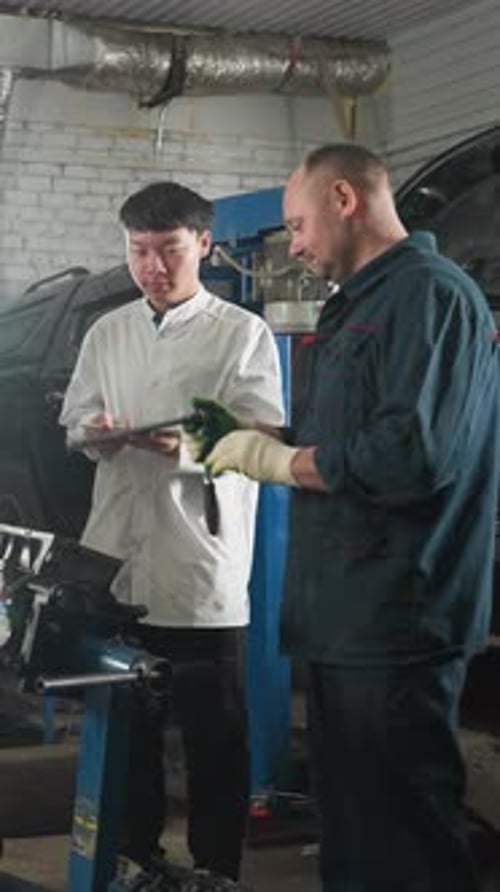 Mechanic Teaching Students Engine Repair in Automotive Workshop