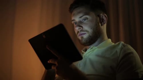Man Using Tablet at Night in Dark Room