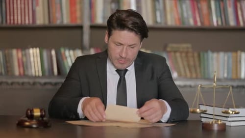 Pensive Male Lawyer Reading Documents in Office