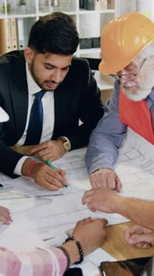 Business Meeting Discussing Blueprints in Office