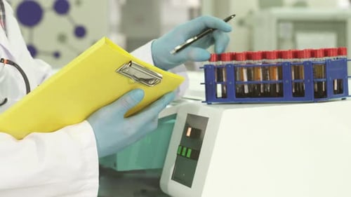 Scientist in Laboratory Looking at Test Tubes