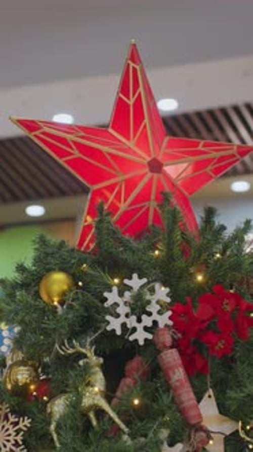 Sapin de Noël festif avec étoile rouge vif et ornements dans un centre commercial décoré