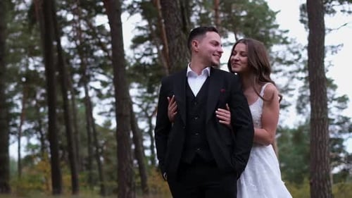 Couple marié, mariée en robe de mariée blanche et marié marchant dans les bois