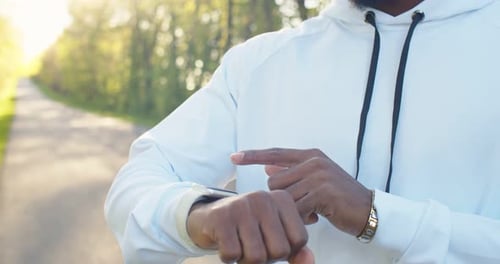 Close Up of Handsome African American Young Male Standing Outdoors on Street and Tapping on Smart