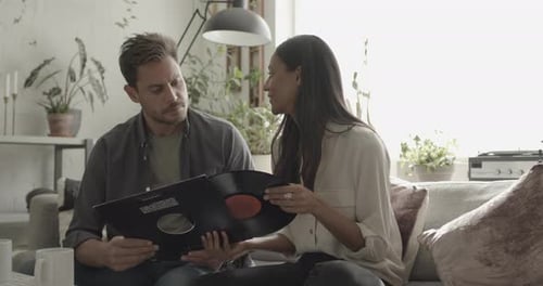 Couple Looking at Vinyl Records on Sofa at Home