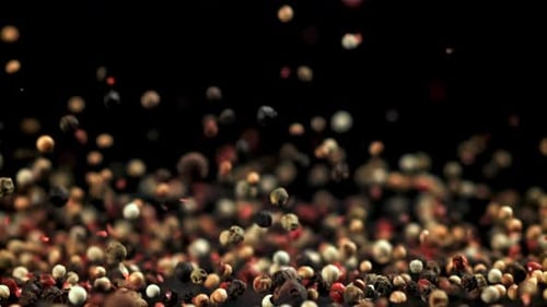 Falling colorful peppercorns on black background