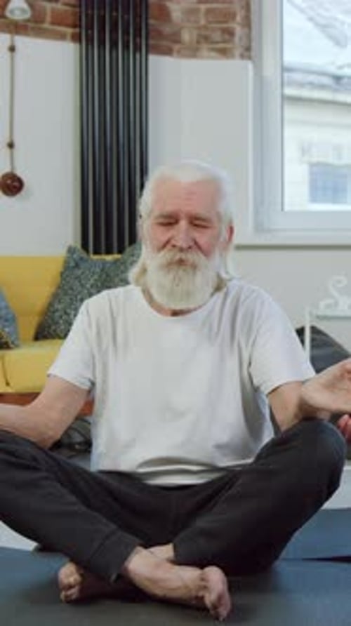 Senior Man Meditating on Yoga Mat in Home