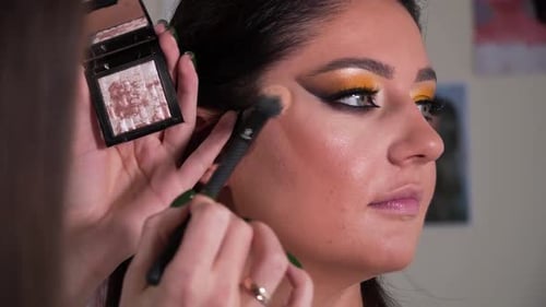 the makeup artist is doing makeup for another woman, brushing highlighter, contouring. closeup shot