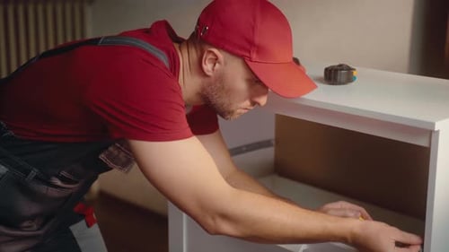 Interior Carpenter Measures and Assembles Furniture in a Bright Home Environment
