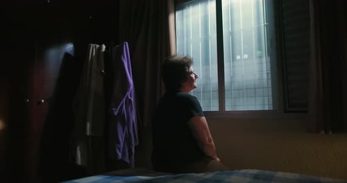 Woman Sitting on Bed Looking Out Window
