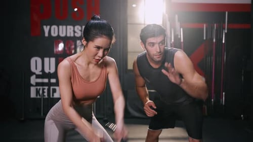 Woman Training With Battle Rope in Gym with Trainer