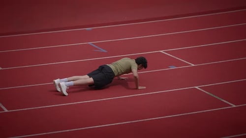 An Athlete Performs Pushups on a Track Field to Boost Fitness and Endurance Levels
