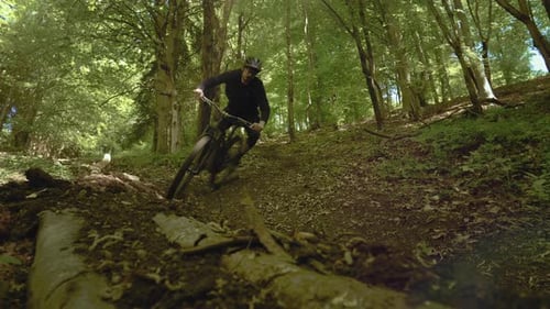 Amazing shot of a biker with MTB E-bike biking down the hill in the forest. Extreme riders.