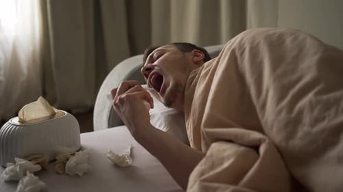Patient de sexe masculin administrant un spray pour la gorge présentant une forte fièvre et restant au lit pendant la maladie