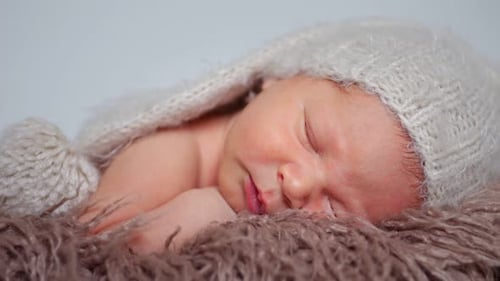 Close up of a sleeping infant wearing knit hat