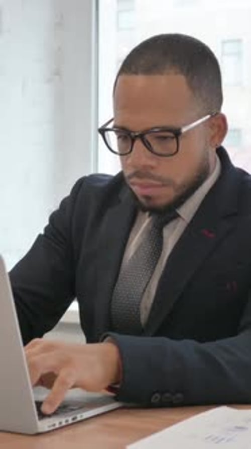 Focused Businessman Working at Desk on Laptop in Office