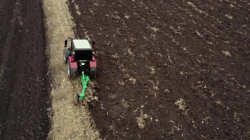 Red tractor plowing the field in Ukraine