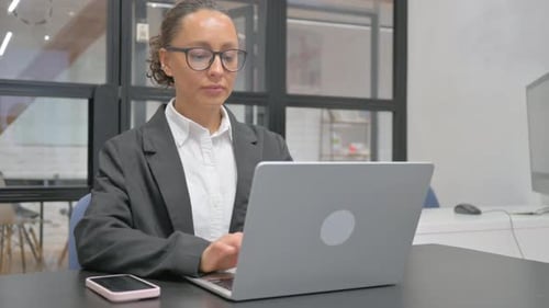 Hispanic Business Woman Working on Laptop in Office