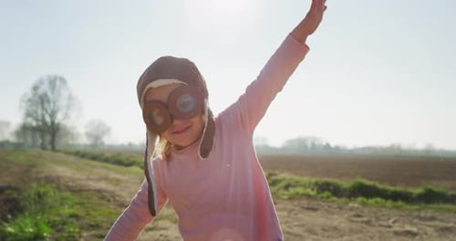 Authentic shot of cute little girl with aviator hat having fun and smiling in camera on a spring n
