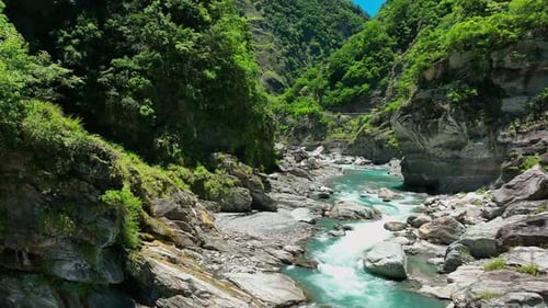 Aerial Establishing Shot Gliding Over a Flowing Stream Between Lush Green Forests