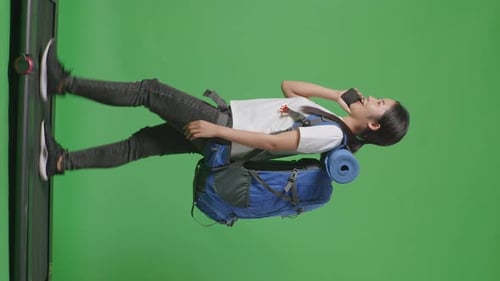 Side View Of Female Hiker Talking On Smartphone While Walking On A Treadmill On Green Screen