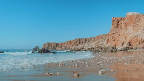 Beautiful rocky beach surrounded by cliffs. Turquoise ocean washing sandy beach. Top surfing spot.