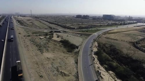 Uma visão aérea em câmera lenta de uma rodovia e cidade, os pesados arrastões e carros estão se movendo na rodovia,