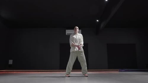 Young Woman Dancing in a Dark Studio with Orange Lighting