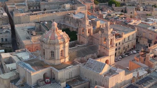 A detailed aerial view of St. Paul's Cathedral in Mdina, Malta, showcasing its baroque dome, twin