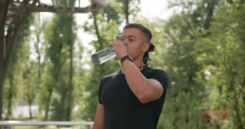 Athletic Man Drinking Water in Park