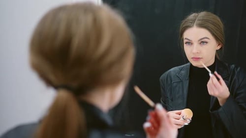 Woman Applying Concealer in Front of Mirror